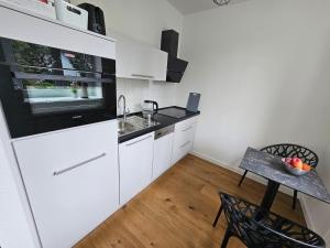 a kitchen with white appliances and a table with a bowl of fruit at Casa Frida - Business flat near BER, kitchen, bathroom, balcony, workspace, 24" Monitor, Wifi, SmartTV, Netflix, car park in Berlin