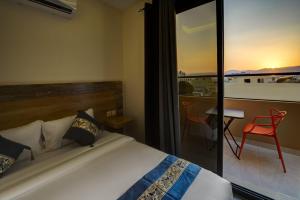a bedroom with a bed and a balcony with a red chair at Three Palms Suites in Aqaba