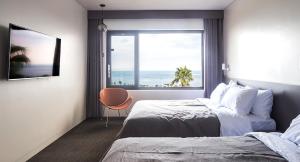 a bedroom with a bed and a window with the ocean at Jeju Bricks Hotel in Seogwipo