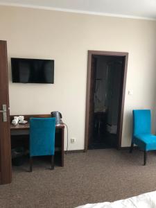 a hotel room with a desk and two blue chairs at Świdnica Kolonia noclegi in Świdnica