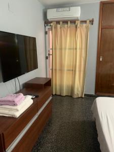 een slaapkamer met een tv en een dressoir met een bed bij Casa cerca del microcentro y costanera in Posadas