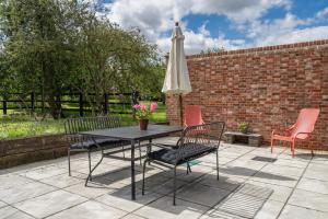 a patio with a table and chairs and an umbrella at Contemporary Barn Waveney Valley in Mendham