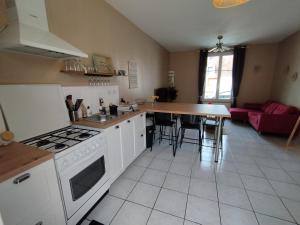 cocina con fogones y mesa. en Maison de campagne proche Beauval, en Selles-sur-Cher