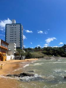 vistas a una playa con edificios en el fondo en Apartamento Guarapari pé na areia com Wi-Fi e Garagem, en Guarapari