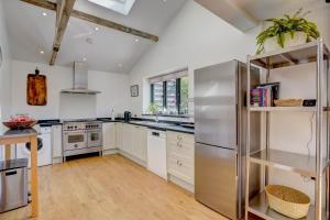 a kitchen with white cabinets and a stainless steel refrigerator at Contemporary Barn Waveney Valley in Mendham
