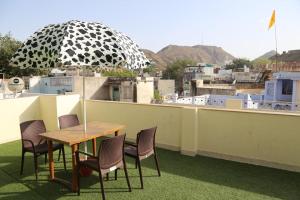 a table and chairs with an umbrella on a roof at KINGSWAY HOTEL AND RESTAURANT Ajmer Dargah 350 Meter in Ajmer