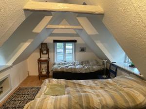 um quarto no sótão com 2 camas e uma janela em Værelser i historisk hus med sjæl og atmosfære em Helsinge