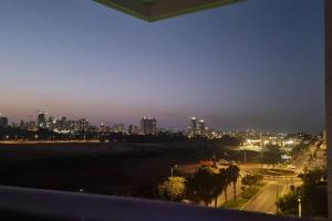 uma vista para o horizonte da cidade à noite em Home way from home em Netanya
