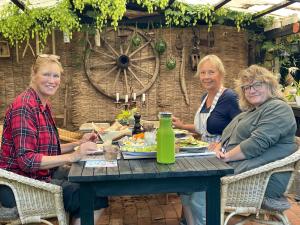 trzy starsze kobiety siedzące przy stole jedzące jedzenie w obiekcie Værelser i historisk hus med sjæl og atmosfære w mieście Helsinge