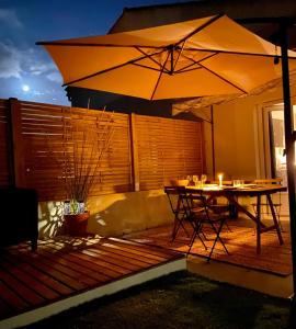 un patio con mesa y sombrilla en Tiny Harmony - Logement confortable avec jardin et jacuzzi privés près d’Aix en Provence, en Venelles
