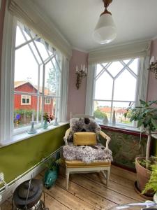Zimmer mit Stuhl in einem Zimmer mit Fenstern in der Unterkunft Gränna Grandeur Stay in Style in Gränna