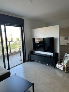 een woonkamer met een grote flatscreen-tv bij Appartement Guivat Olga 4 pièces proche mer in H̱adera