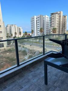 balcón con mesa y vistas a la ciudad en Appartement Guivat Olga 4 pièces proche mer, en H̱adera