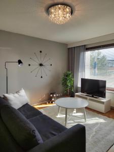 ein Wohnzimmer mit einem Sofa, einem Tisch und einer Uhr in der Unterkunft City Apartment Tieva in Rovaniemi