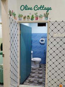 a blue bathroom with a toilet and a blue door at Olive Cottage in Kampong Ru Lima