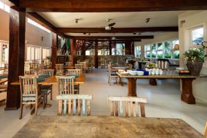 a restaurant with wooden tables and chairs and windows at Pousada Camburizinho in Camburi