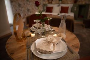 un tavolo con piatti, bicchieri da vino e una rosa di Le Mas aux Amoureux , Suite Romantique et Spa a Le Barcarès