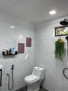 La salle de bains blanche est pourvue d'une douche et de toilettes. dans l'établissement Abe.Cottage 2, à Kampung Kuala Besut
