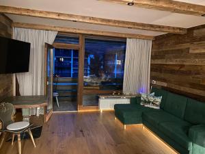 a living room with a green couch and a table at Chalet Grubhof in Sankt Martin bei Lofer