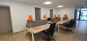 una oficina con escritorios, sillas y lámparas de naranja en Maison de la Lionne, en Luchon