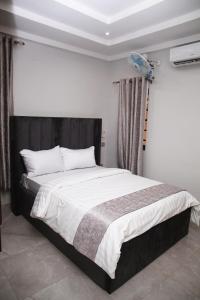 um quarto com uma cama grande e lençóis brancos em Newly Built 2 Bedroom Tastefully Furnished House Available For Shortlet. em Lagos