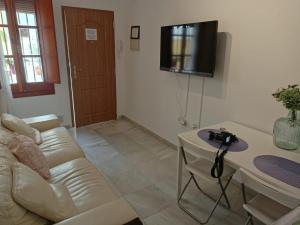 a living room with a white couch and a television on the wall at Apartamento Dueñas in Seville