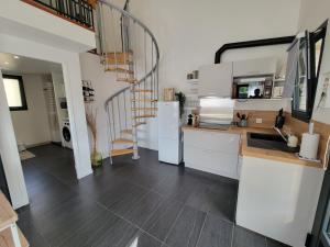 une cuisine avec des placards blancs et un escalier en colimaçon dans l'établissement Les Cabanes de l'Airial Ecume, à Andernos-les-Bains