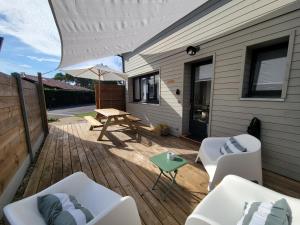 a patio with a picnic table and chairs and an umbrella at Les Cabanes de l'Airial Ecume in Andernos-les-Bains