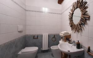 a bathroom with a sink and a toilet and a mirror at Casa Adua in Donoratico +35 photos