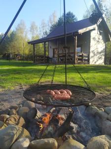 a grill with two sausages cooking over a fire at Zbychowskie Zacisze in Zbychowo