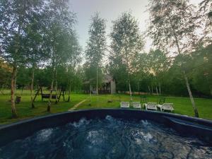 a hot tub in a yard with chairs and a house at Zbychowskie Zacisze in Zbychowo