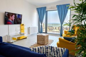 a living room with blue furniture and a large window at Dream Mamaia North in Năvodari