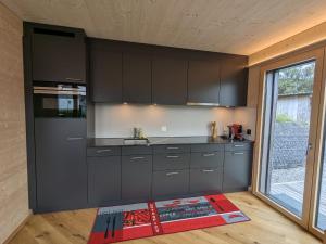 a kitchen with black cabinets and a large window at TinyHouse - (D)ein Ferienhaus in Schellenberg