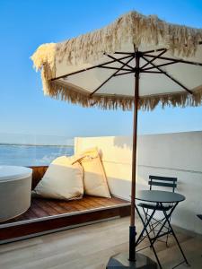 un tavolo con un ombrello di paglia accanto a un letto di Palazzo Matà Boutique Hotel a Taranto