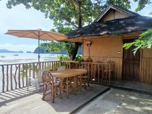 a wooden deck with a table and chairs and an umbrella at Hut Sunset Island View in El Nido