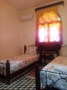 um quarto com 2 camas e uma janela com sombra de janela em Hotel TOURAGHINE em Chefchaouen