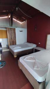 two beds in a room with red walls at Cabañas Palos Locos in Baru