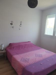 een roze bed in een witte kamer met een raam bij Appartement F4 Le Milena in Saint-Paul-et-Valmalle