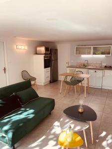 sala de estar con sofá verde y cocina en Appartement indépendant avec jardin et accès piscine, en Nimes