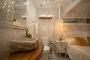 a bathroom with a sink and a toilet and a bed at Casinhas do Miga in Santa Comba Dão