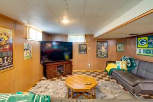 a living room with a couch and a flat screen tv at Retro Green Bay Home Steps to Lambeau Field! in Green Bay