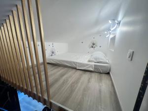 een slaapkamer met een bed op een houten vloer bij Maison Appartement Triplex avec jacuzzi et sauna in Saint-Étienne