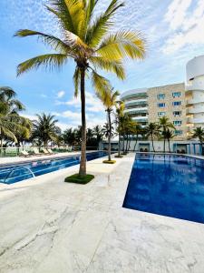 a swimming pool with a palm tree in front of a building at Apartamento Delux Morros-Tolusa in Cartagena de Indias