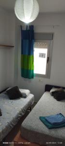 a room with two beds and a window with a rainbow curtain at Disfruta Granada,incluso con tu mascota Parking in Granada