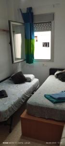 a bedroom with two beds and a window with a rainbow flag at Disfruta Granada,incluso con tu mascota Parking in Granada
