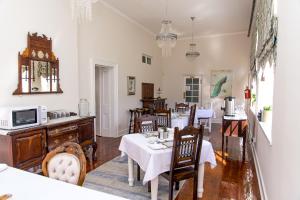 uma sala de jantar com mesas e cadeiras e um relógio em Herberg Manor em Somerset East