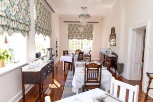 uma sala de jantar com mesas, cadeiras e janelas em Herberg Manor em Somerset East