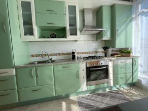 uma cozinha verde com armários brancos e um lavatório em Appartement T1 Centre Pombal em Pombal