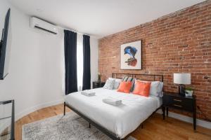 Ce lit se trouve dans une chambre dotée d'un mur en briques. dans l'établissement Les Lofts du Plateau, à Montréal