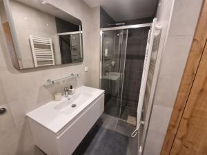 La salle de bains blanche est pourvue d'un lavabo et d'une douche. dans l'établissement Velký byt 3+kk Klicperova, 2 ložnice, à Hradec Králové